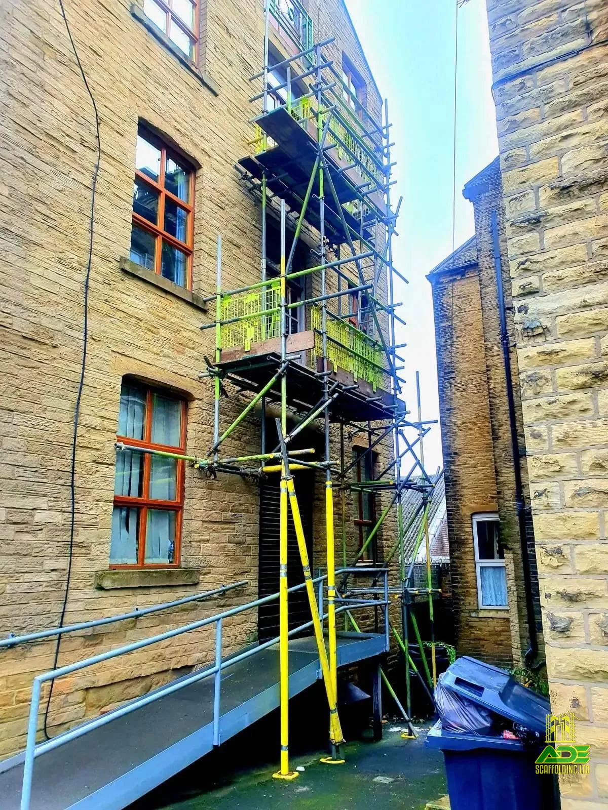 Multi-lift scaffold in a narrow alley between stone buildings