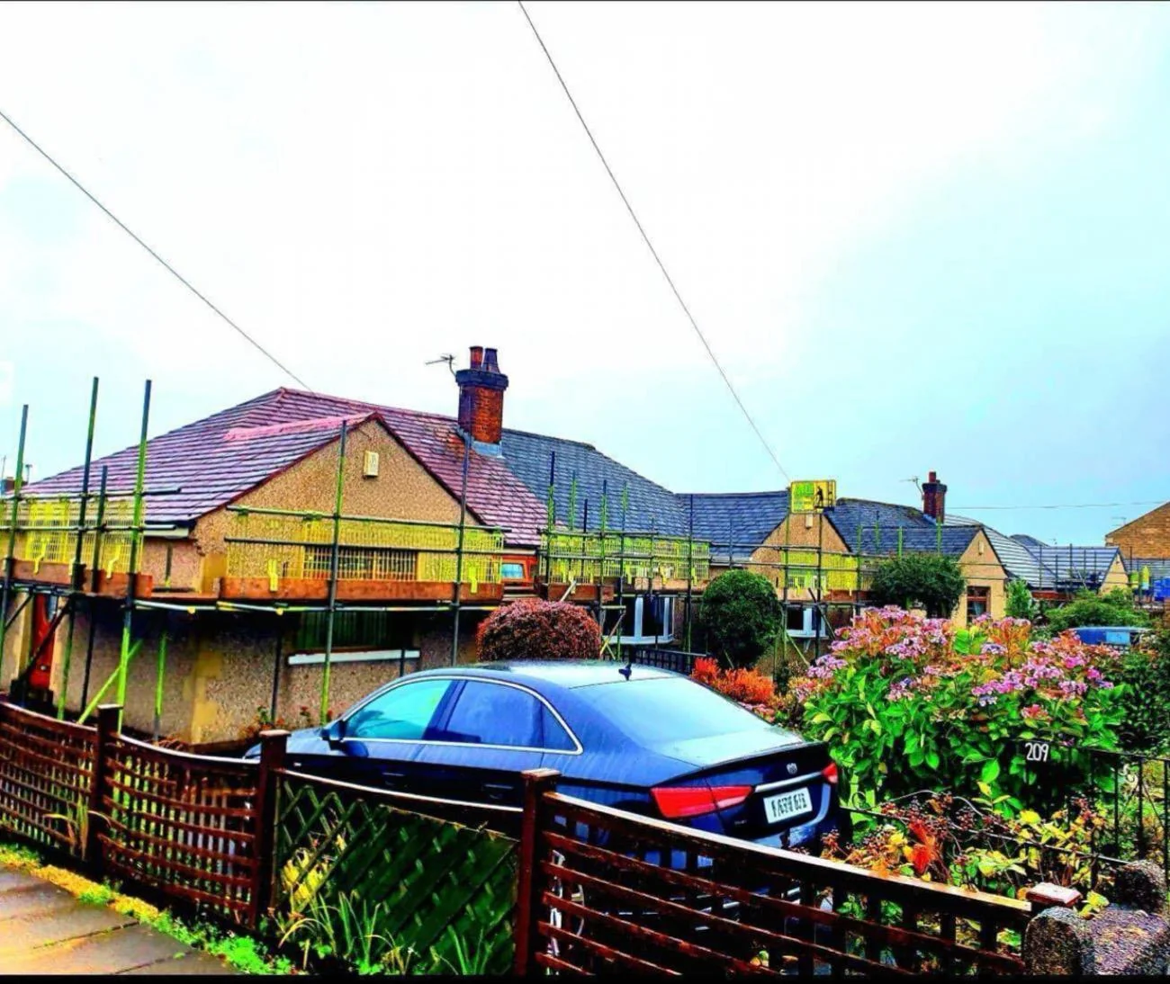 Low-lift eaves scaffold across a chalet bungalow row with ADE banners